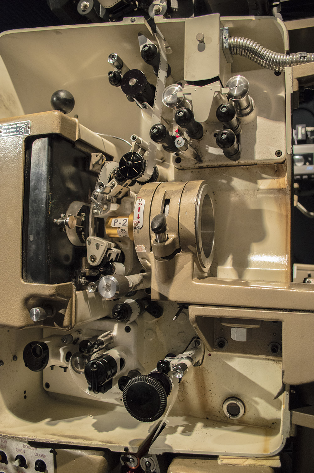 The mechanism of a Philips DP70 projector, cream painted metal with black control knobs, with film threaded through it.